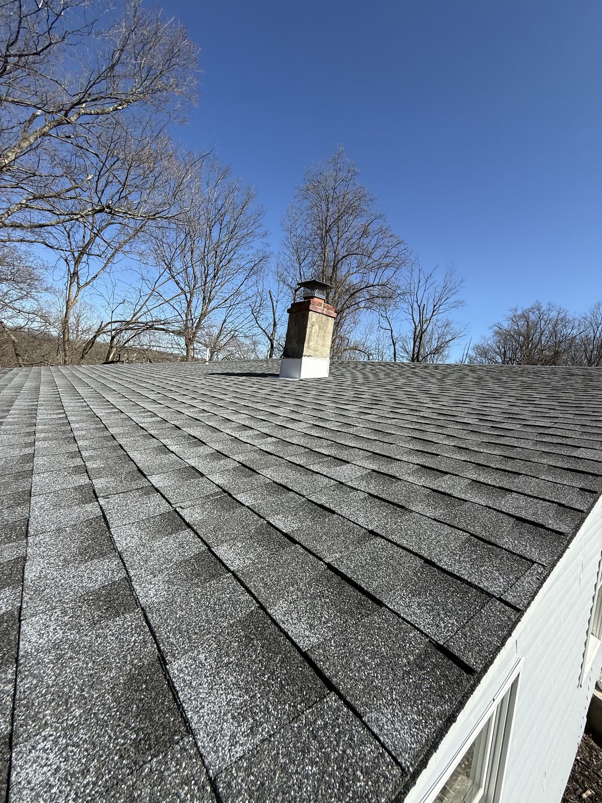 Completed grey architectural shingle roof with chimney flashing