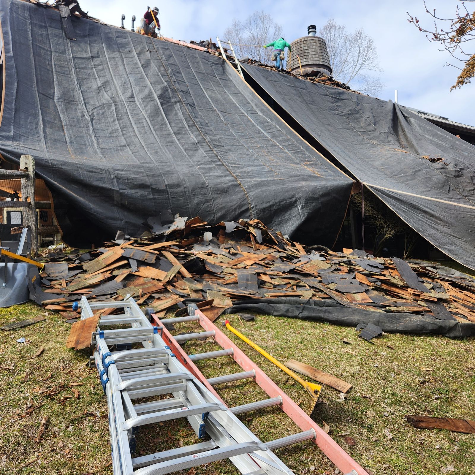 Cedar shake debris piled on tarps beside a fully protected building