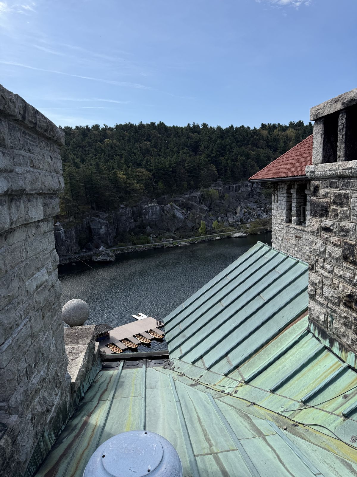 Patinated copper standing seam roof on a stone landmark building above a lake