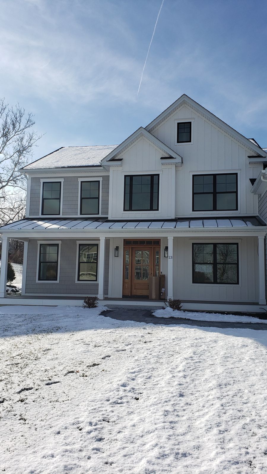 White farmhouse with standing seam porch roof, board and batten and shake siding