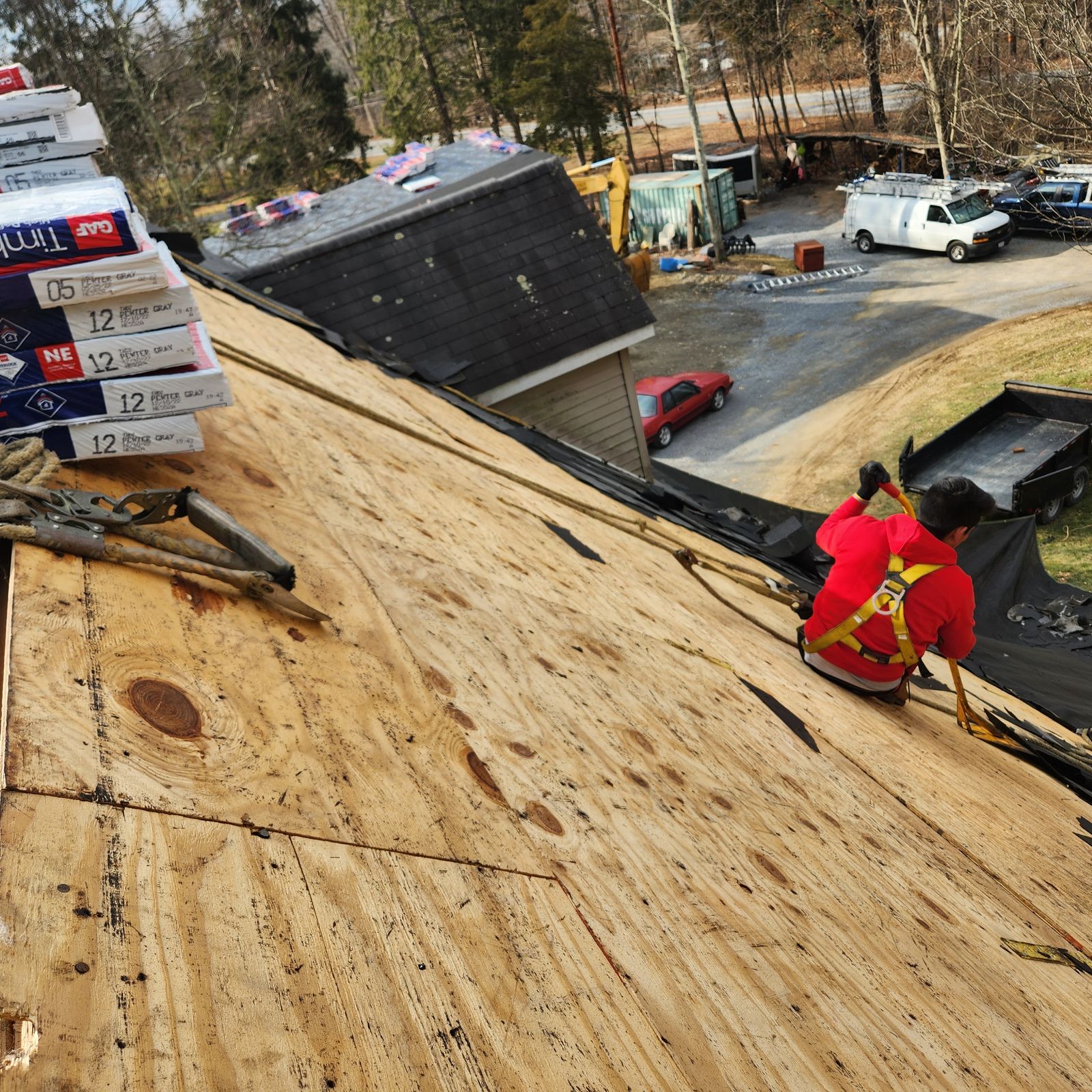 Roofer in a safety harness on newly installed plywood decking