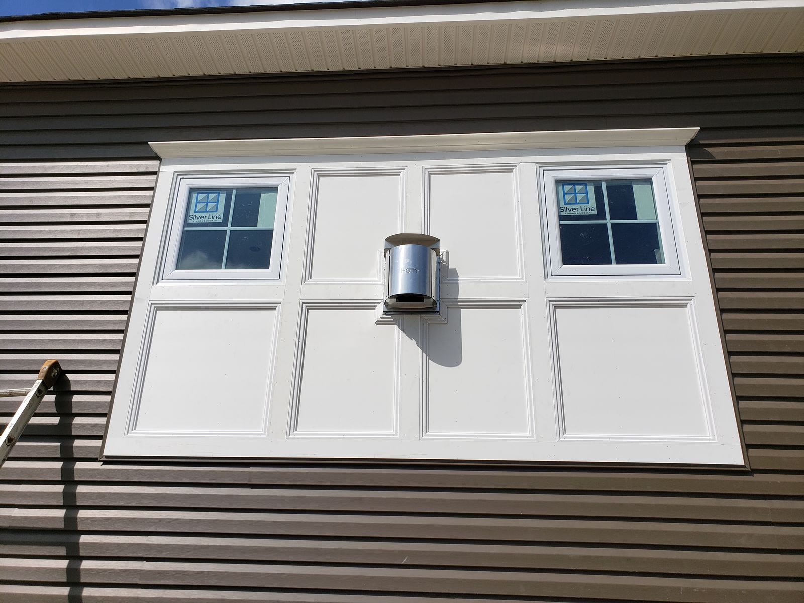 Vinyl siding with a white paneled accent surround and trimmed windows