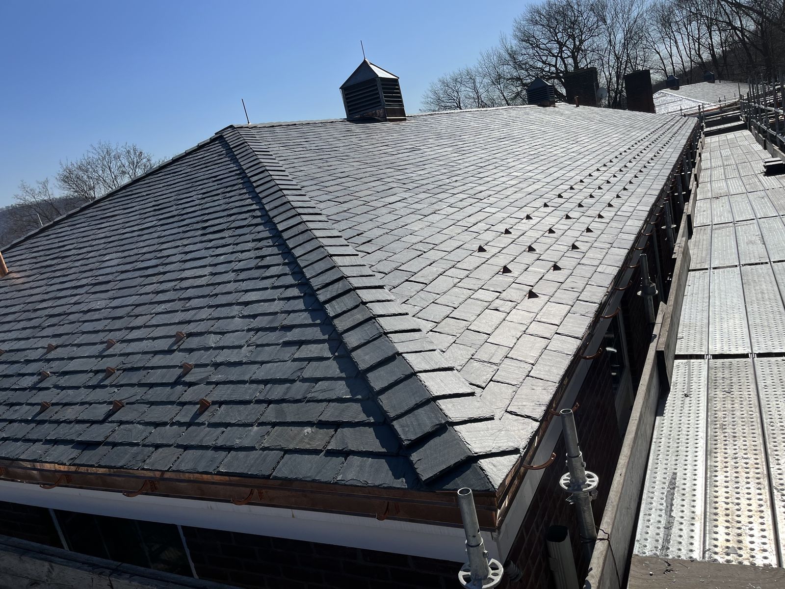 Large natural slate roof with copper gutter and snow guards